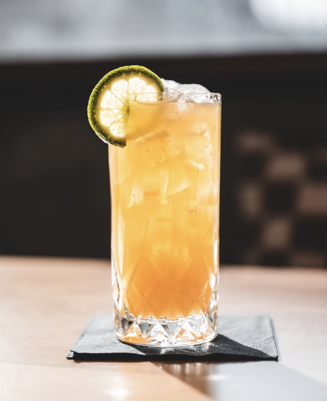 Crystal-cut highball with amber spirit and a fresh lime wheel
